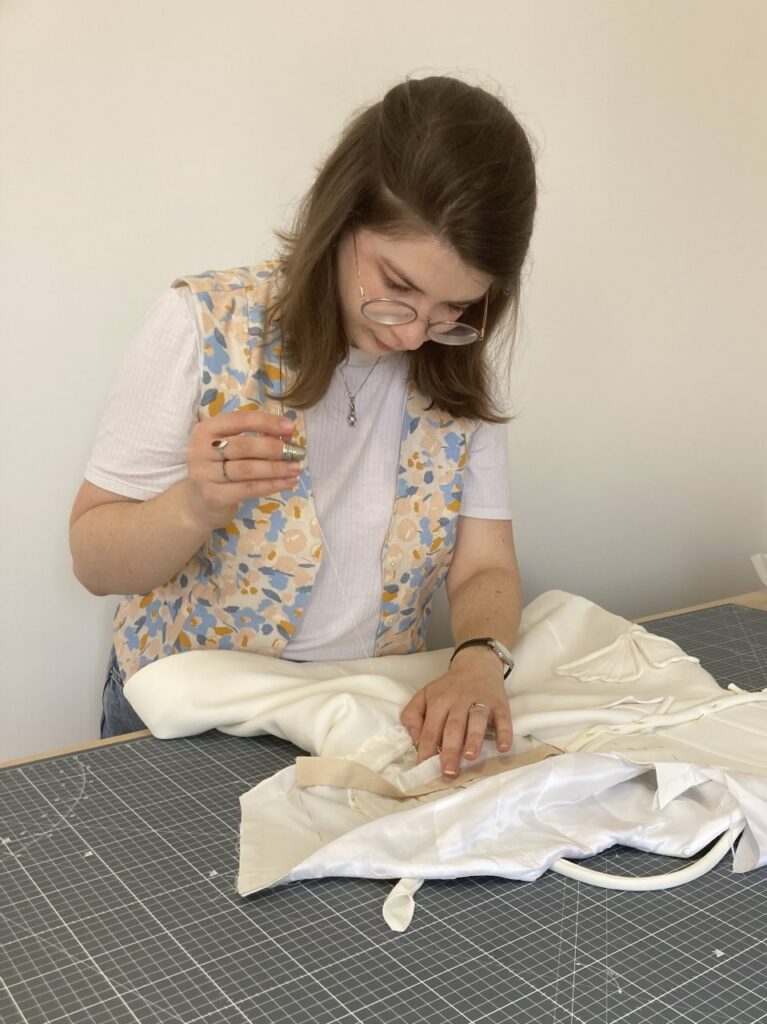 Couturière cousant à la main une robe de mariée sur-mesure au Havre